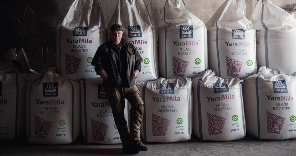 Farmer standing in front of YaraMila bags with Recycled stamp